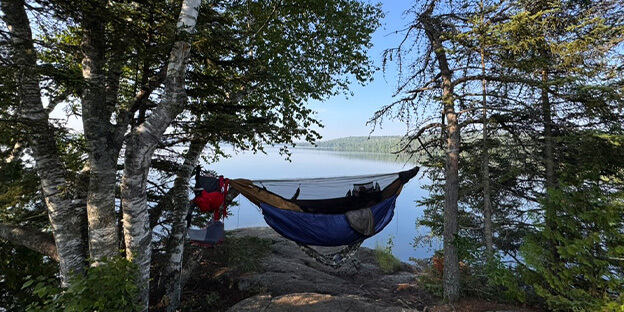 a picture of a man in a hammock overlooking the boundary waters