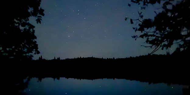 a picture of the night time stars are shining over a lake