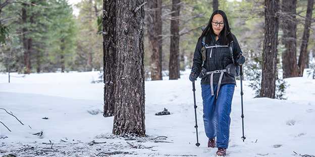 a women walking on a snowy trail wearing navy enlightened equipment torrid pants