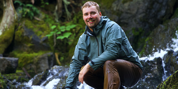 A man in the wilderness waring a rain visp jacket